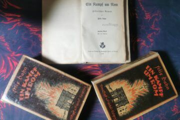Drei alte Bücher mit dem Titel "Ein Kampf um Rom" von dem Autor Felix Dahn, eines davon aufgeschlagen auf der ersten Seite.