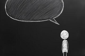 Ein Strichmännchen ohne Gesichtszüge vor einem dunklen Hintergrund mit einer leeren Sprechblase