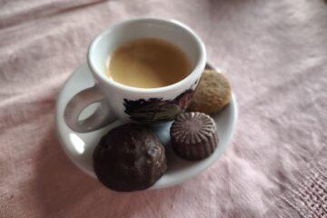 eine gefüllte bunte espressotasse mit drei süßigkeiten auf dem unterteller