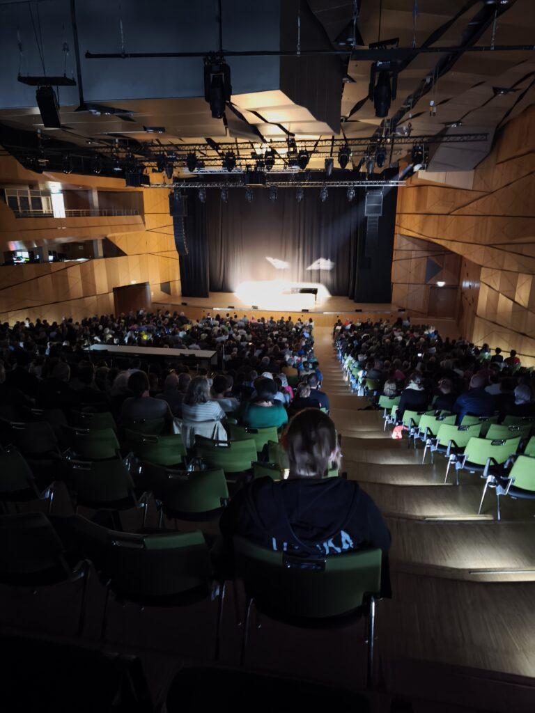 Der große Saal im Darmstadtium von hinten gesehen mit spotbeleuchteter Bühne